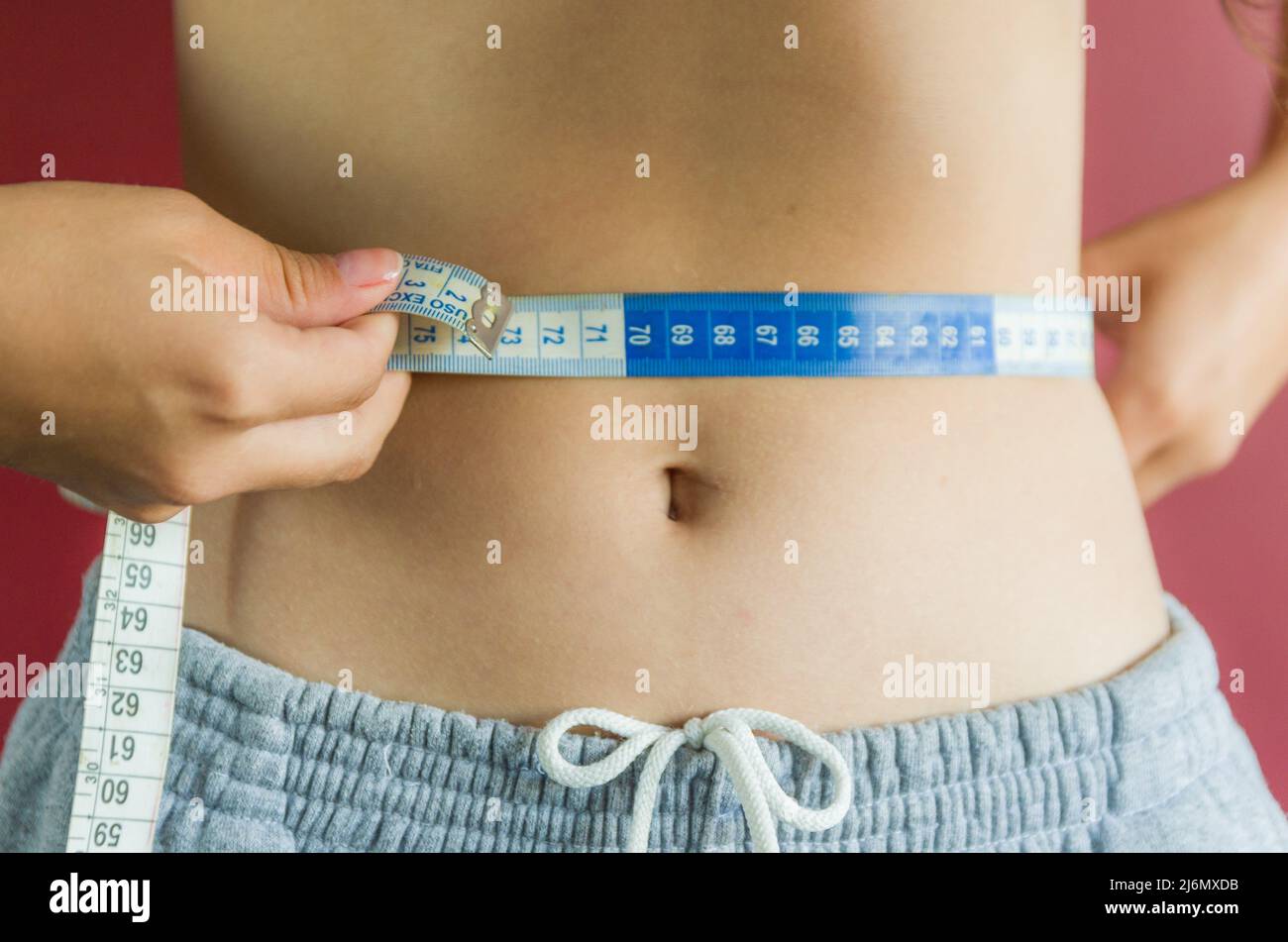 Skinny young woman measuring her slim waist with a measuring tape Stock