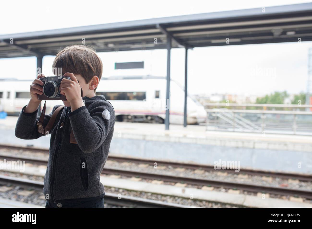 Child boy taking pictures at railway station. Travel on train with children concept. Stock Photo