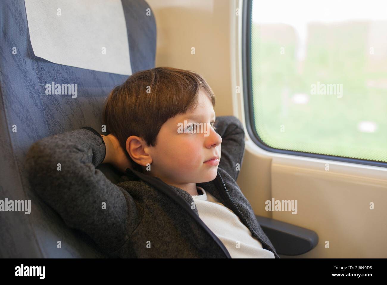 Child traveling by train comfortably. He is thoughtful. Stock Photo