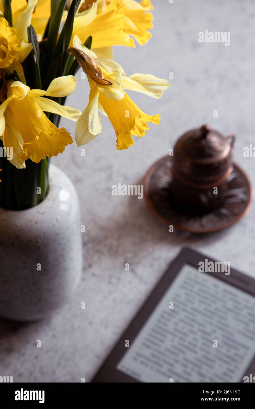 Modern ebook reader,  daffodils flowers on background. Top view, minimal flat lay style composition. Women desk, fashion blogger, beauty technology Stock Photo