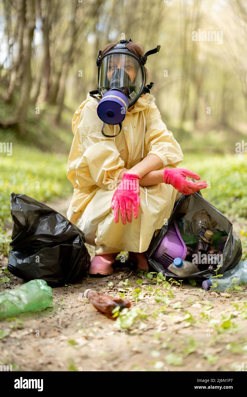 Garbege Protection Mask Woman in gas mask and protective clothes collecting scattered plastic ...