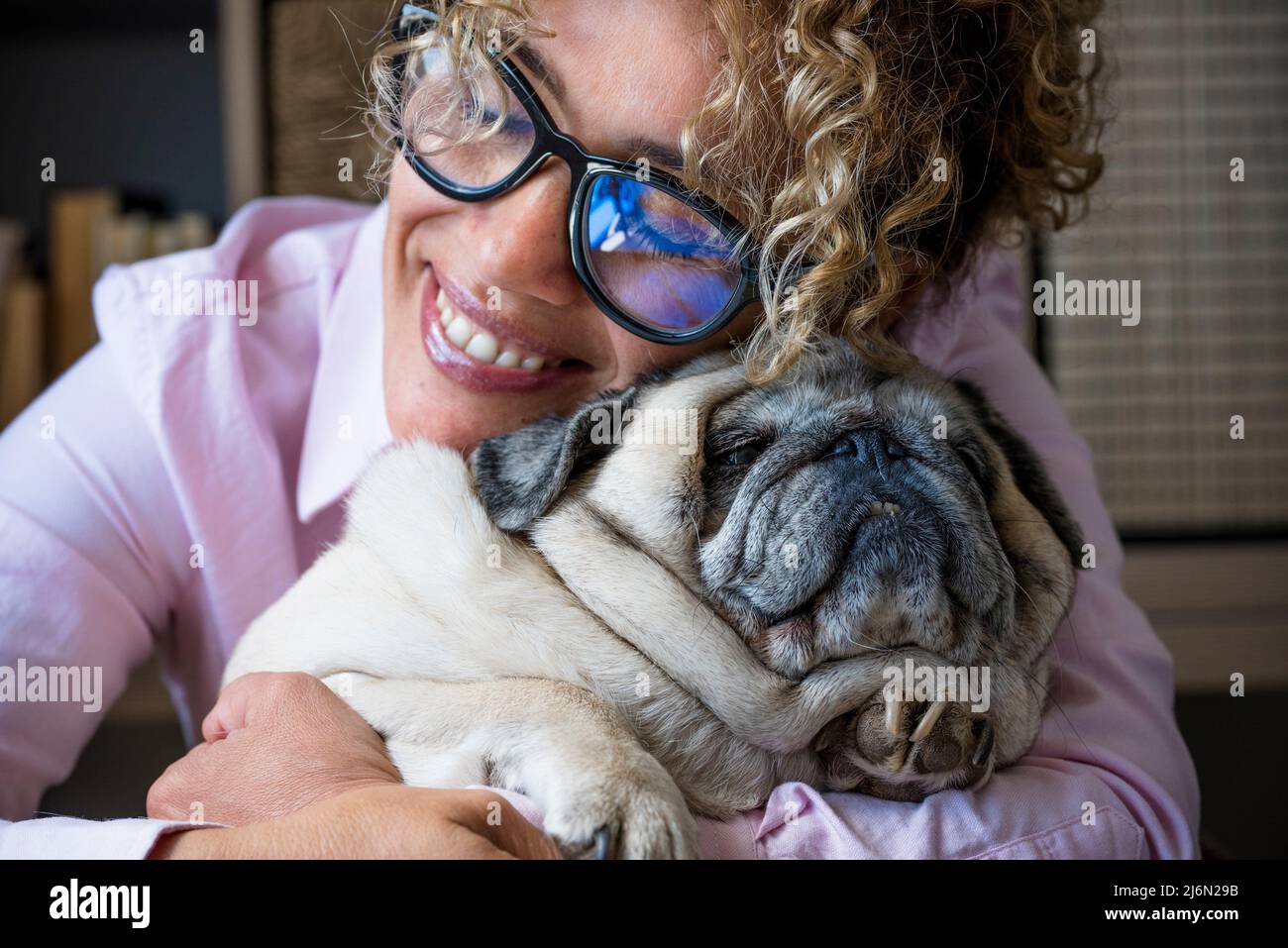 Happy woman hug his dog pug with love and frienship. concept of best friend forever and animal owner enjoying time at home - close up of affection Stock Photo