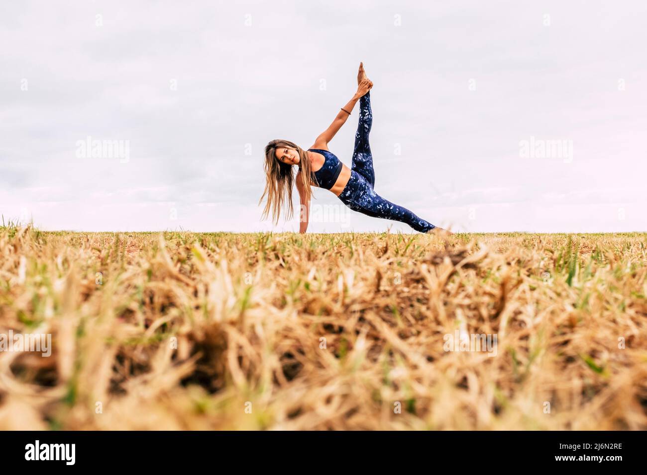Healthy young woman do sport pilates exercises outdoor at the park enjoying body care and happy lifestyle - concept of workout with yoga balanced Stock Photo