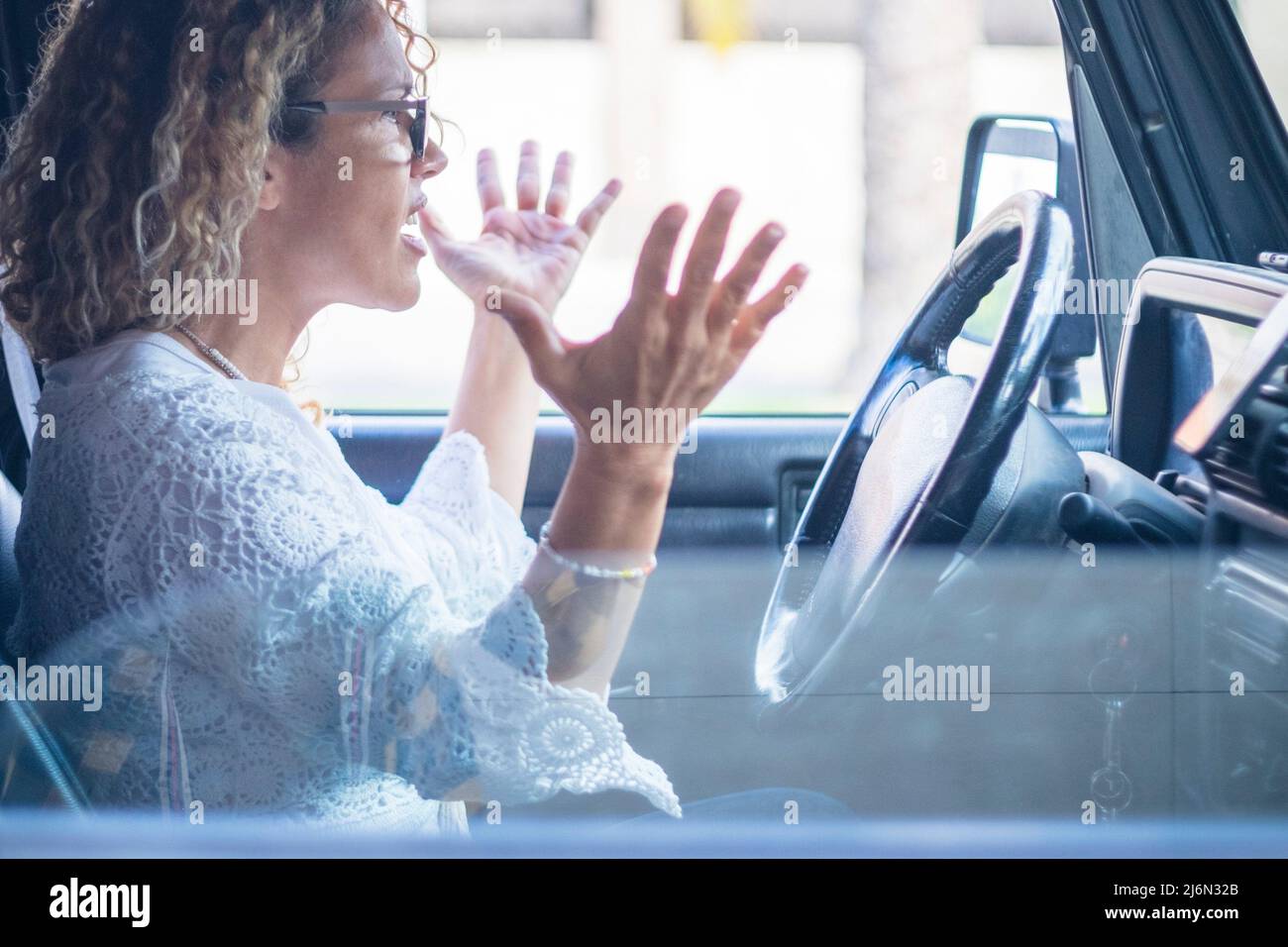 Angry woman driver shout in the traffic - stressed adult people inside car vehicle - hands off of steering wheels safety concept. Stock Photo