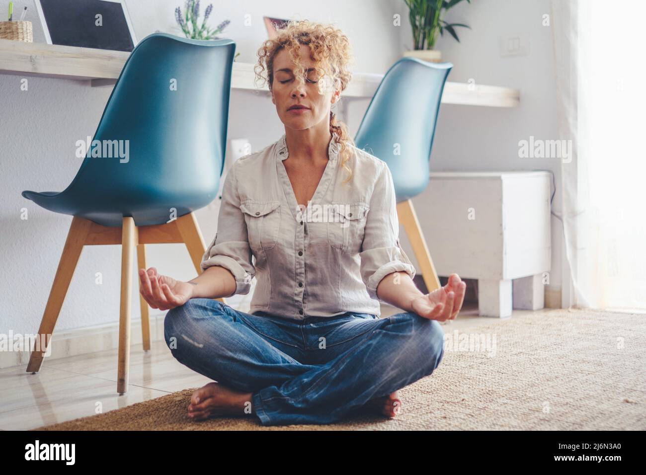 Zen healthy female people do yoga position and meditation at home on the carpet floor - adult woman and mental health or positive lifestyle leisure Stock Photo