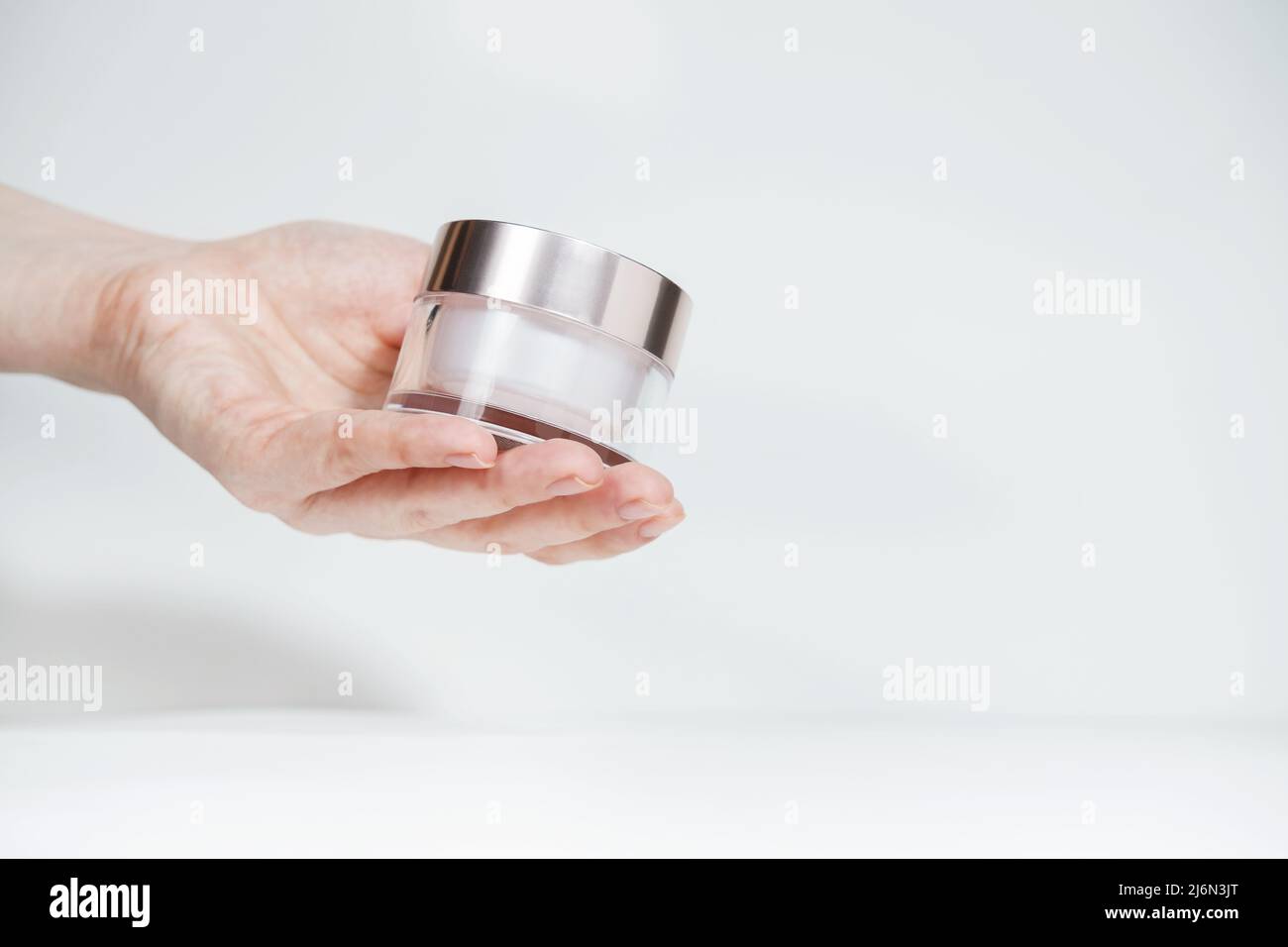Female hand holding mockup unbranded plastic cosmetic tube. Flacon for cosmetic cream, toiletry. Skincare and beauty concept with copy space. Bottle f Stock Photo