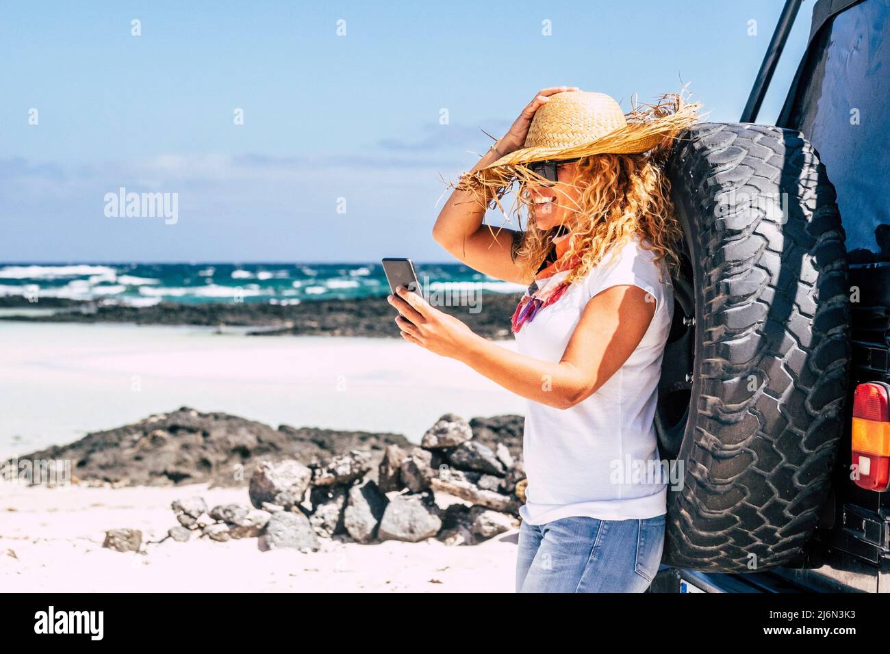 Happy woman smile and use phone roaming connection at the beach in car travel summer holiday vacation outdoor leisure activity alone - free traveler Stock Photo