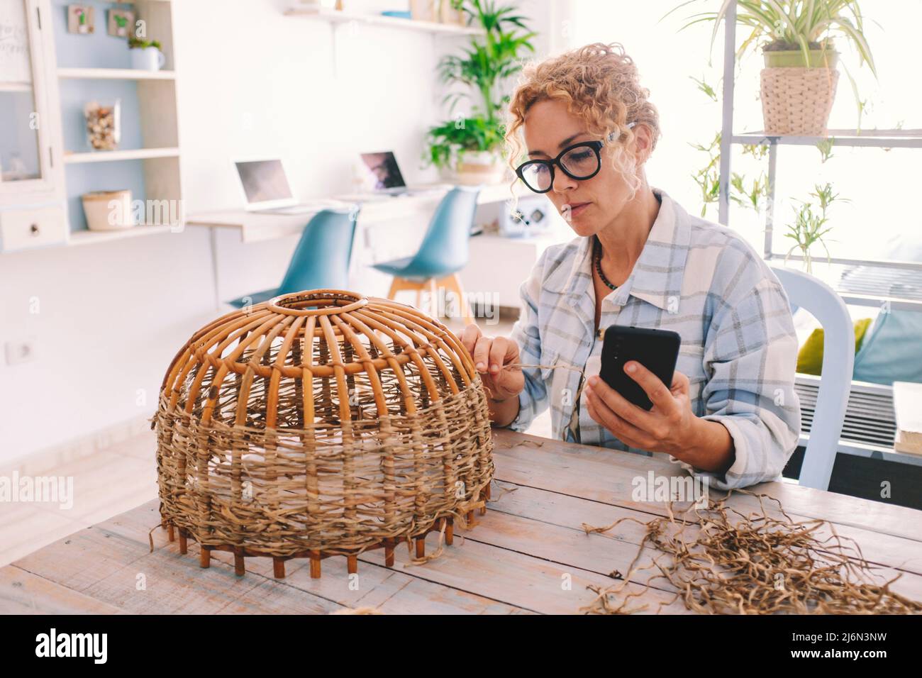 Woman at home doing hobby leisure activity following online tutorial on mobile phone. Modern people and internet content classes do realize and Stock Photo