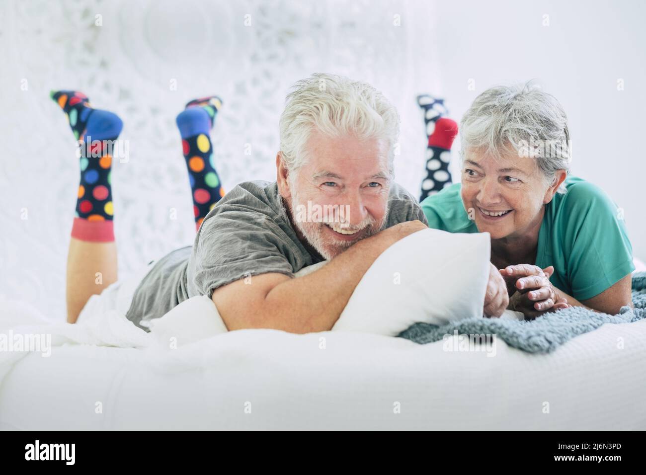 Senior couple lying on front and smiling on bed. Elderly couple
