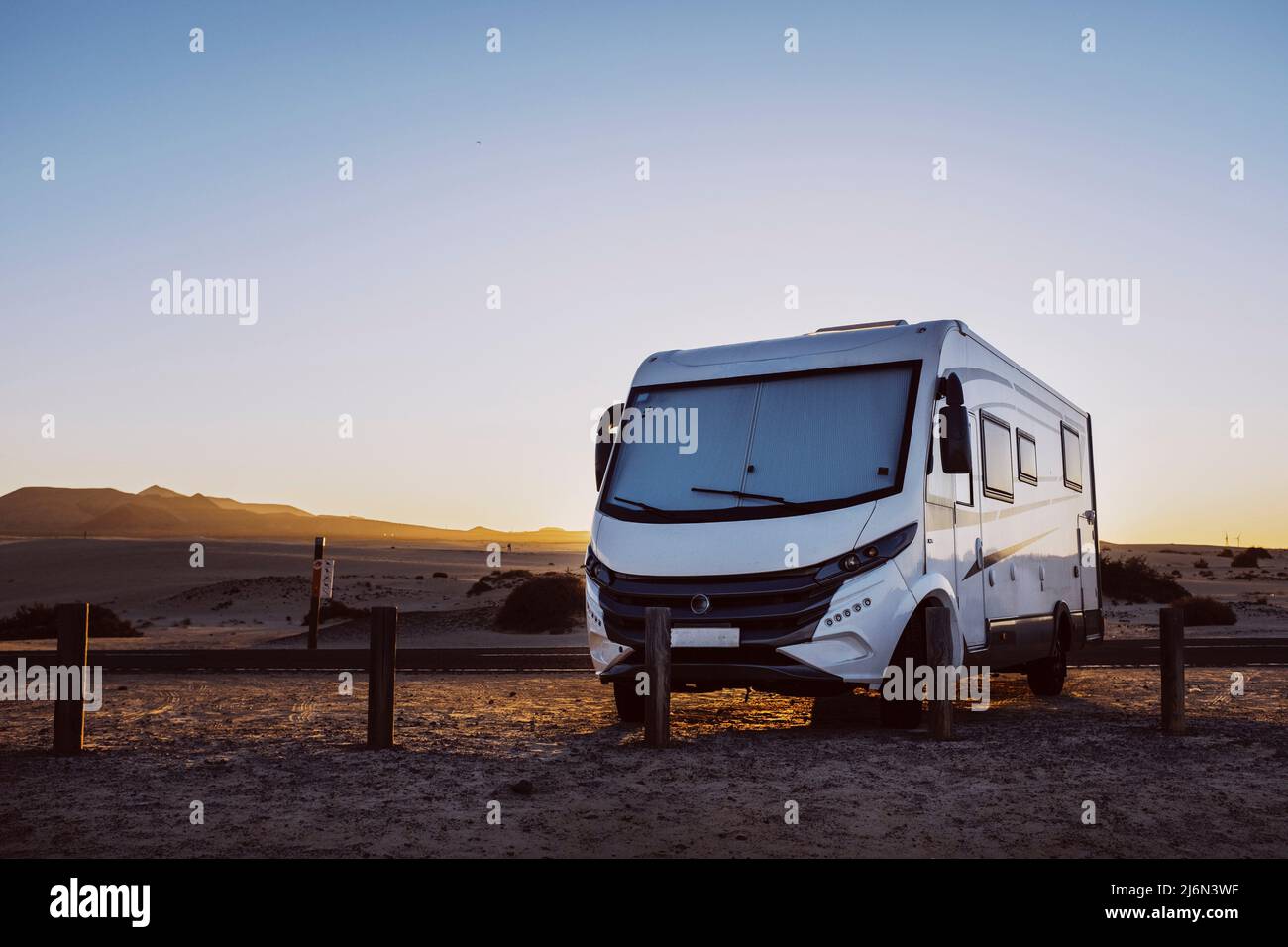 Big motorhome camper parked off road with desert and blue sky in background. Travel lifestyle camping car and freedom. Van against sunlight parked Stock Photo