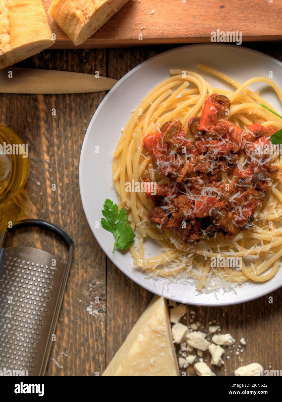Bucatini Bolognese Pasta Dish eith bread and cheese top view on natural wood table. Stock Photo