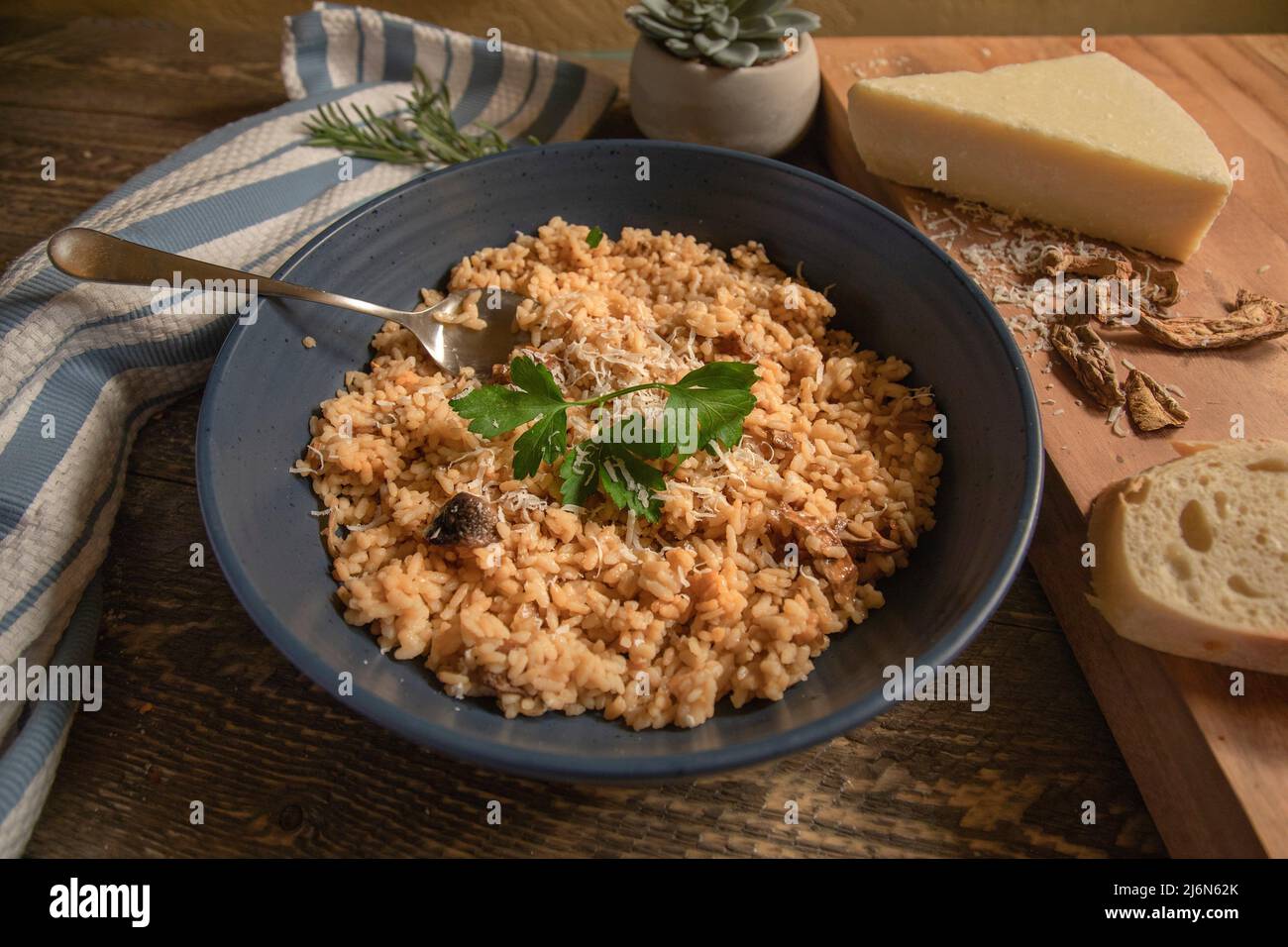 Bowl of Risotto with Cheese, Dried Porcini Mushrooms and Fresh Bread on a natural wood table. Stock Photo
