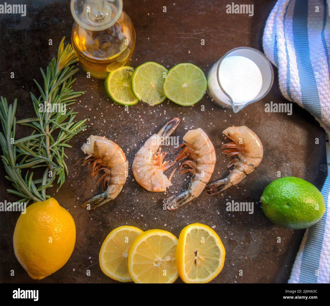 Top view of raw Gulf Shrimp on metal surface with limes, lemons and olive oil. Stock Photo