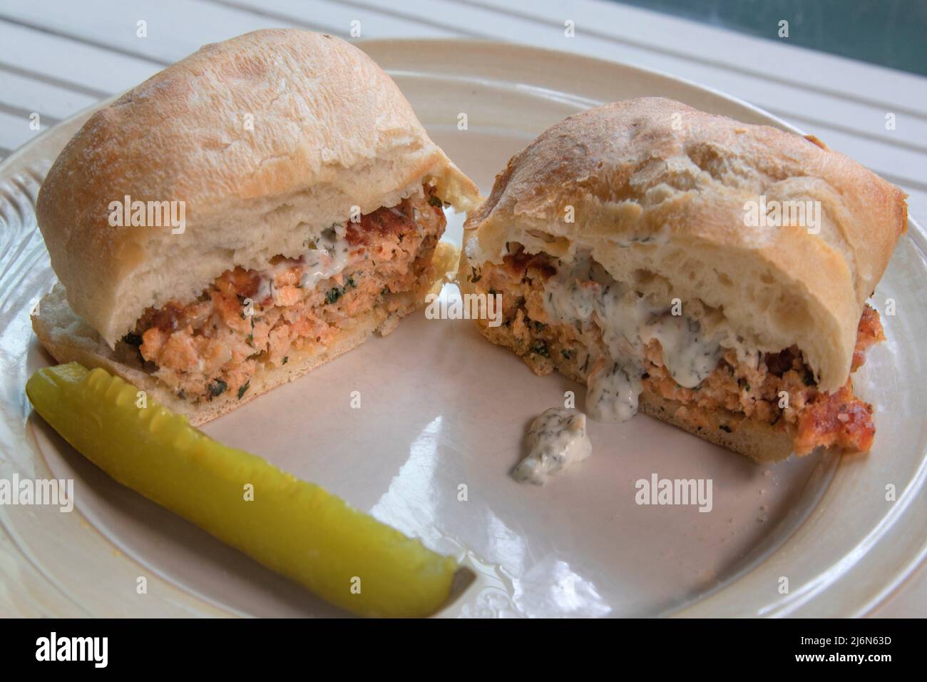 Grilled Salmon Burger on Ciabatta on natural white wood surface. Stock Photo