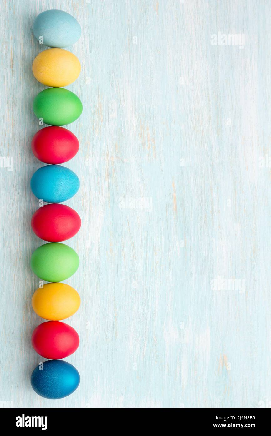 Colorful easter eggs on a blue background, top view, space, vertical Stock Photo