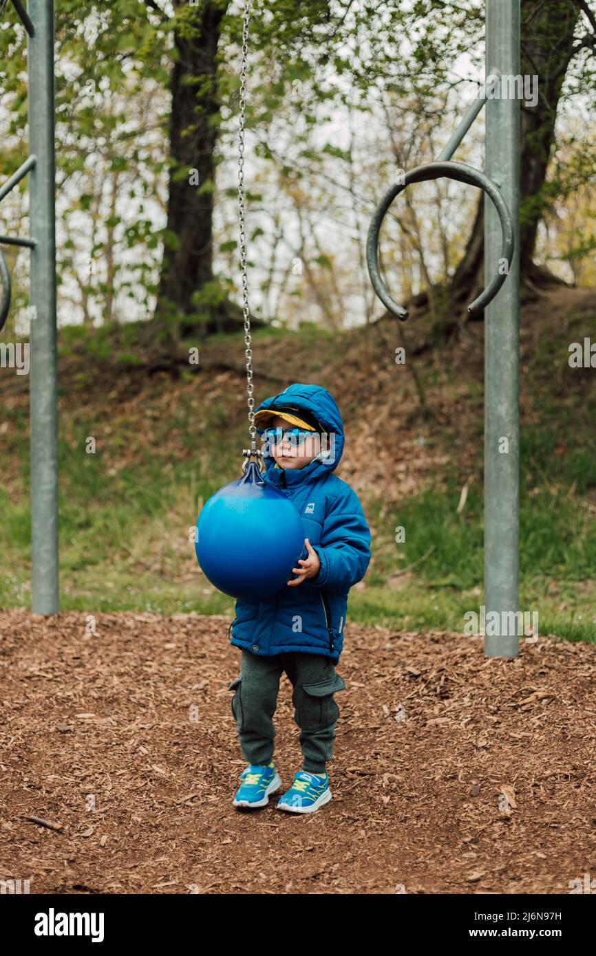 A little boy holds a punching bag in a park on the street Stock Photo