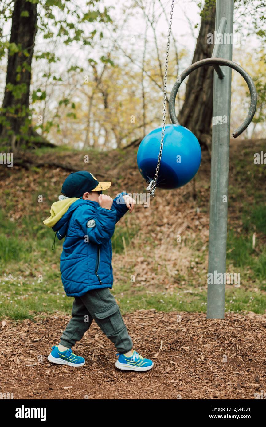 A little boy in a jacket goes in for sports and hits a punching bag Stock Photo
