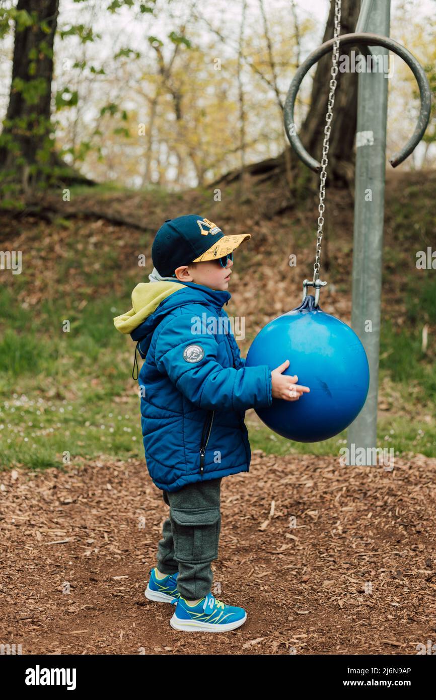 A little boy holds a punching bag in a park on the street Stock Photo