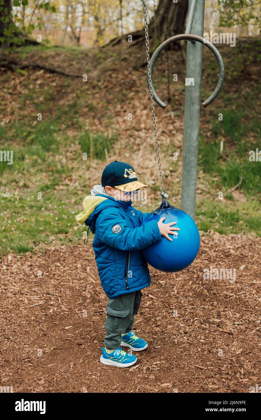 A little boy holds a punching bag in a park on the street Stock Photo