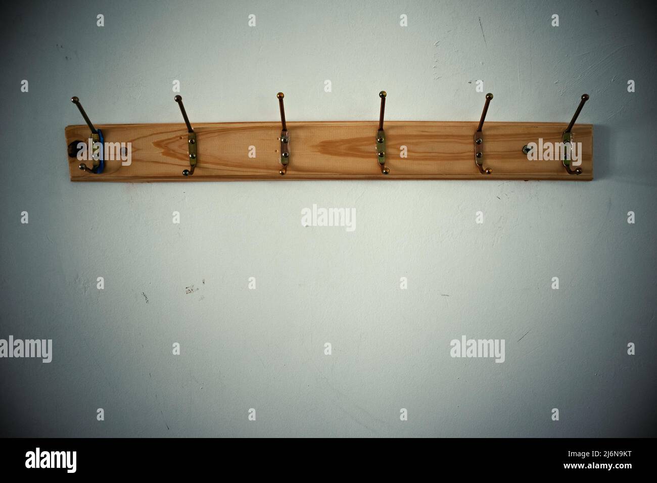 Wooden frame with old metal hangers on the wall, empty space below. Stock Photo
