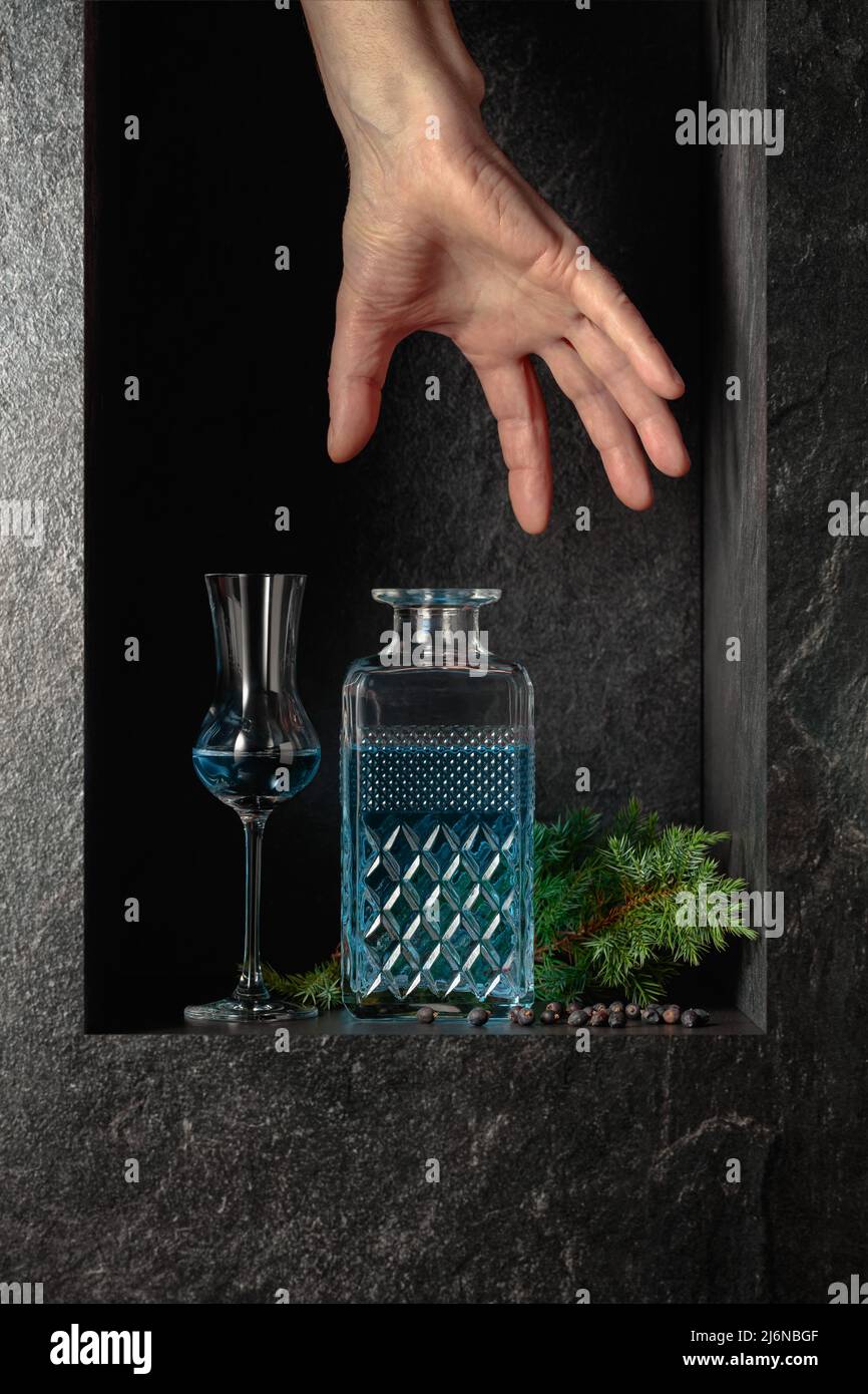 Hand reach for a decanter of gin. A concept image on the theme of