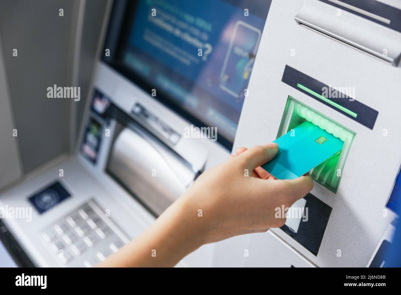 Close up of a girl inserting a credit card in ATM bank machine to transfer money or withdraw. Finance customer and banking service concept Stock Photo