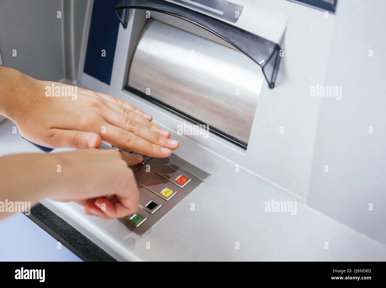 Closeup of hands entering and hiding PIN number password code on ATM
