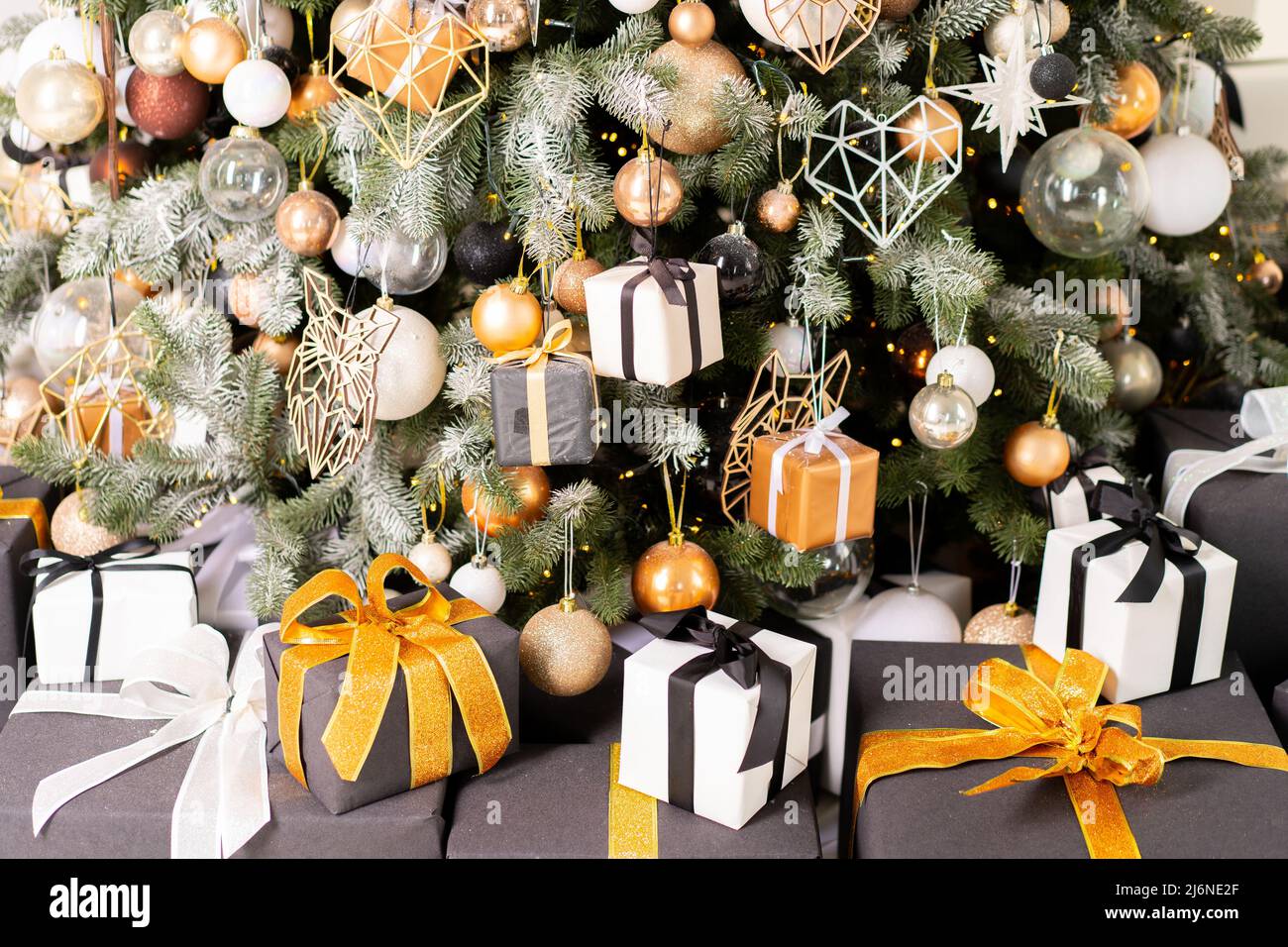 Christmas present gift box stacked close up. Holiday sale concept. Many  gift box black, white, orange color with gold ribbon and light garland  Stock Photo - Alamy, image size:1300x956