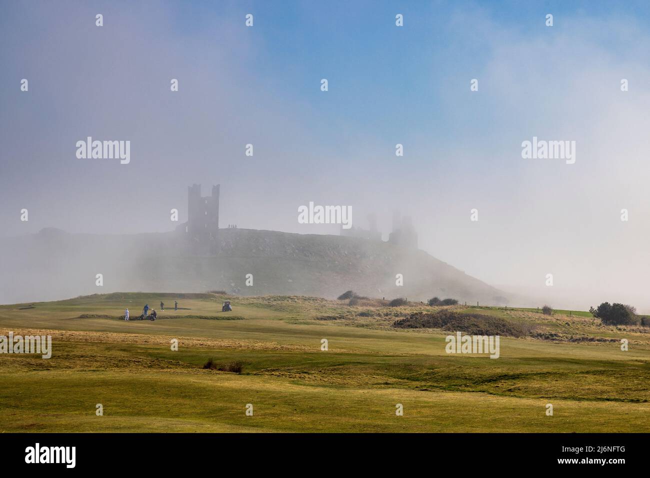 Across the golf course with Dunstanburgh Castle in the sea mist, Northumberland Coast Path, England Stock Photo