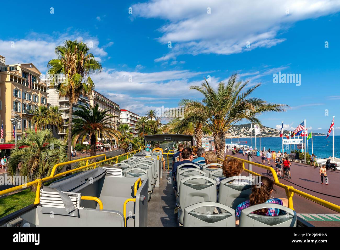 Tourists on sightseeing tour bus passing by buildings and Promenade des Anglais along Mediterranean sea coastline in Nice, France. Stock Photo