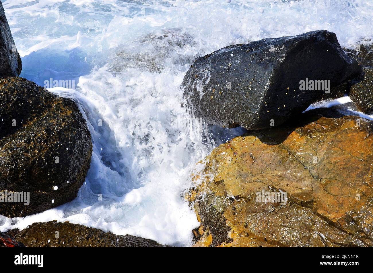 Sea waves are splashing against the hard rocks. Close up of waves splashing against rocks. Sea Photography. Stock Photo