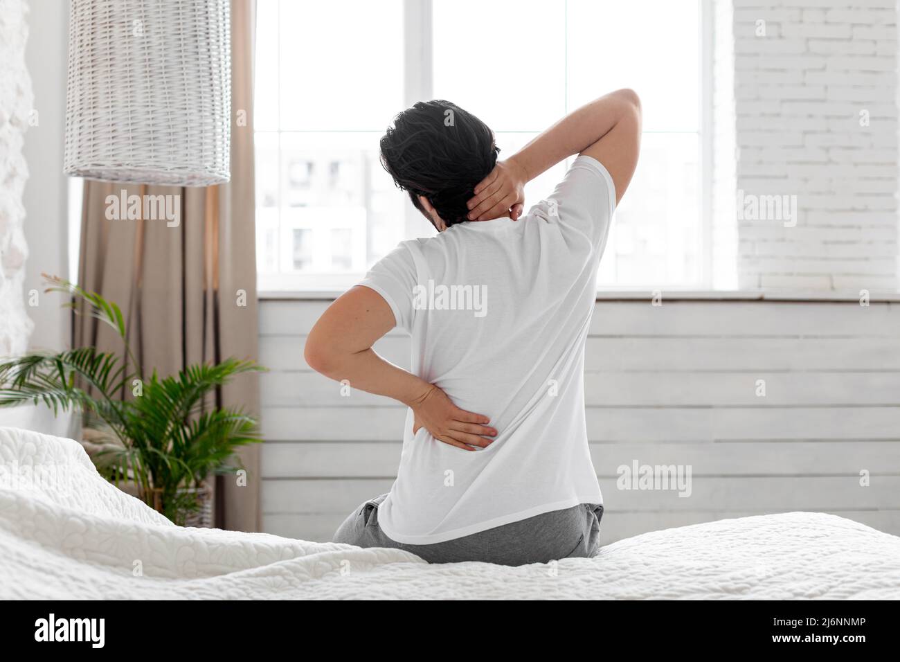 Unrecognizable man suffering from back pain at home in bedroom Stock ...