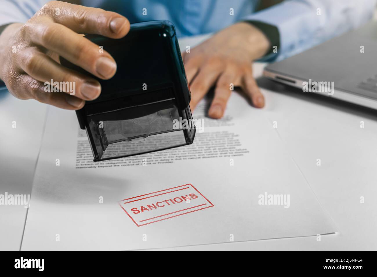 man puts a stamp on sanctions list document Stock Photo