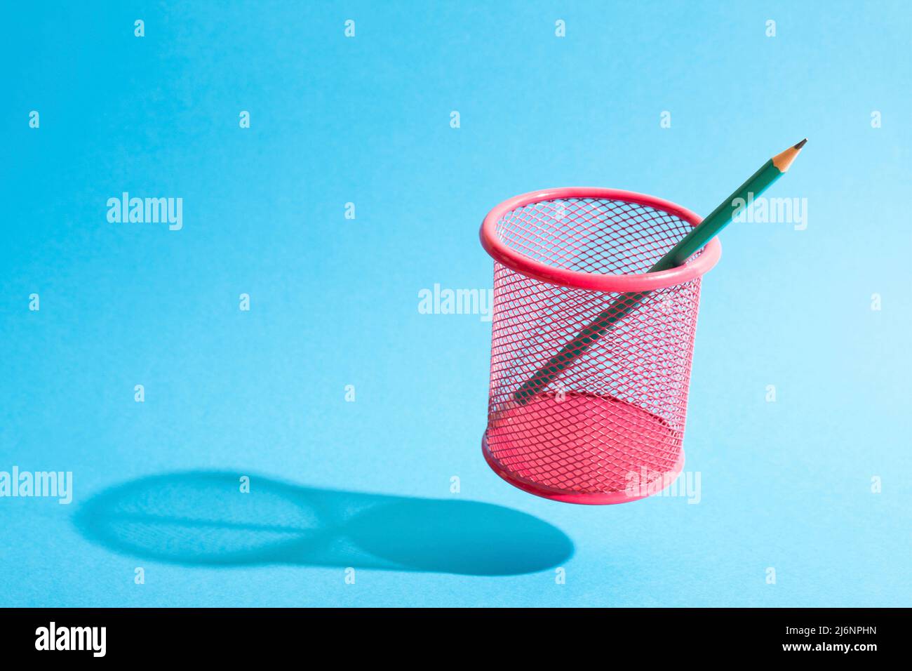 A pencil on a flying fink mesh pencil cup on blue background Stock