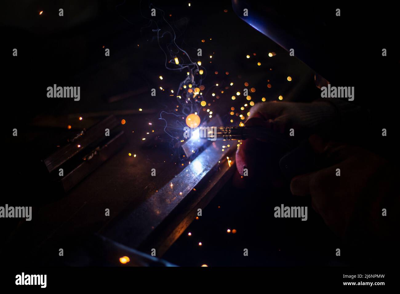 Metal welding. Blue light. Sparks from heating of steel. Welder works in Production of
