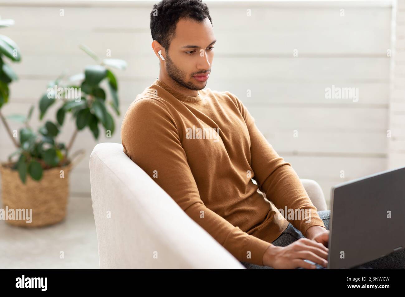 Arab man using laptop sitting on couch at home Stock Photo