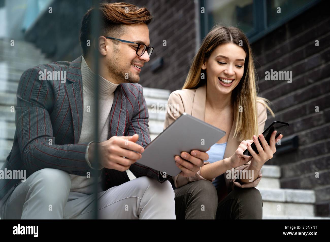 Successful young business people talking, working together in front of modern business building Stock Photo