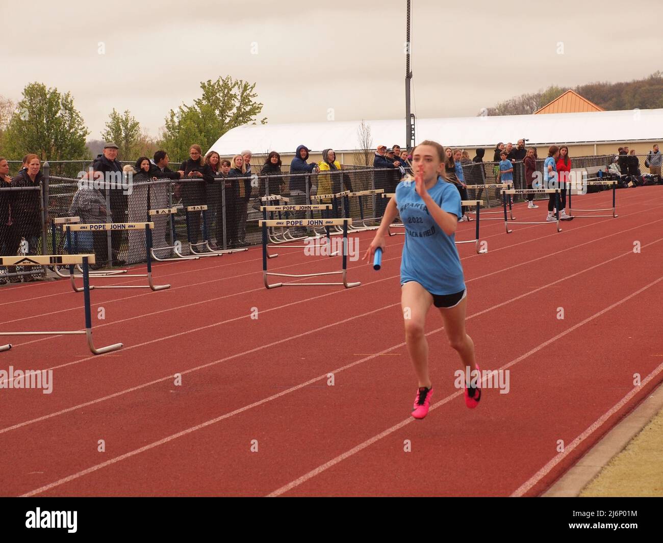 Young female sprinter racing the finish line in a middle school track