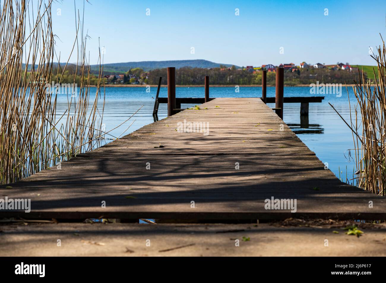 Ground-level shot of a jetty protruding into a blue lake Stock Photo