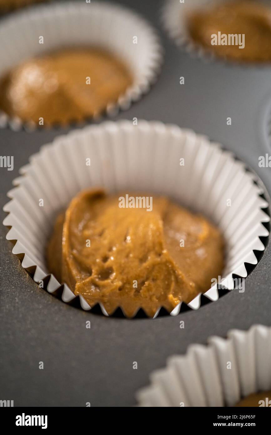 Scooping cupcake batter with a dough scoop into cupcake foil liners to