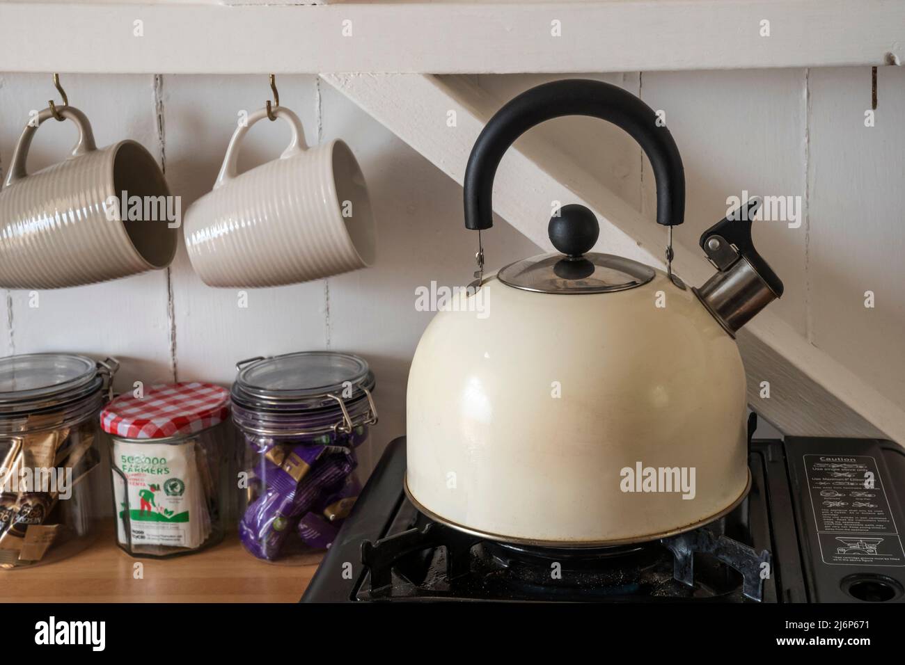 Boiling a kettle on a portable camping gas stove to make a cup of tea in a beach hut at Wells-next-the-Sea on the North Norfolk coast. Stock Photo