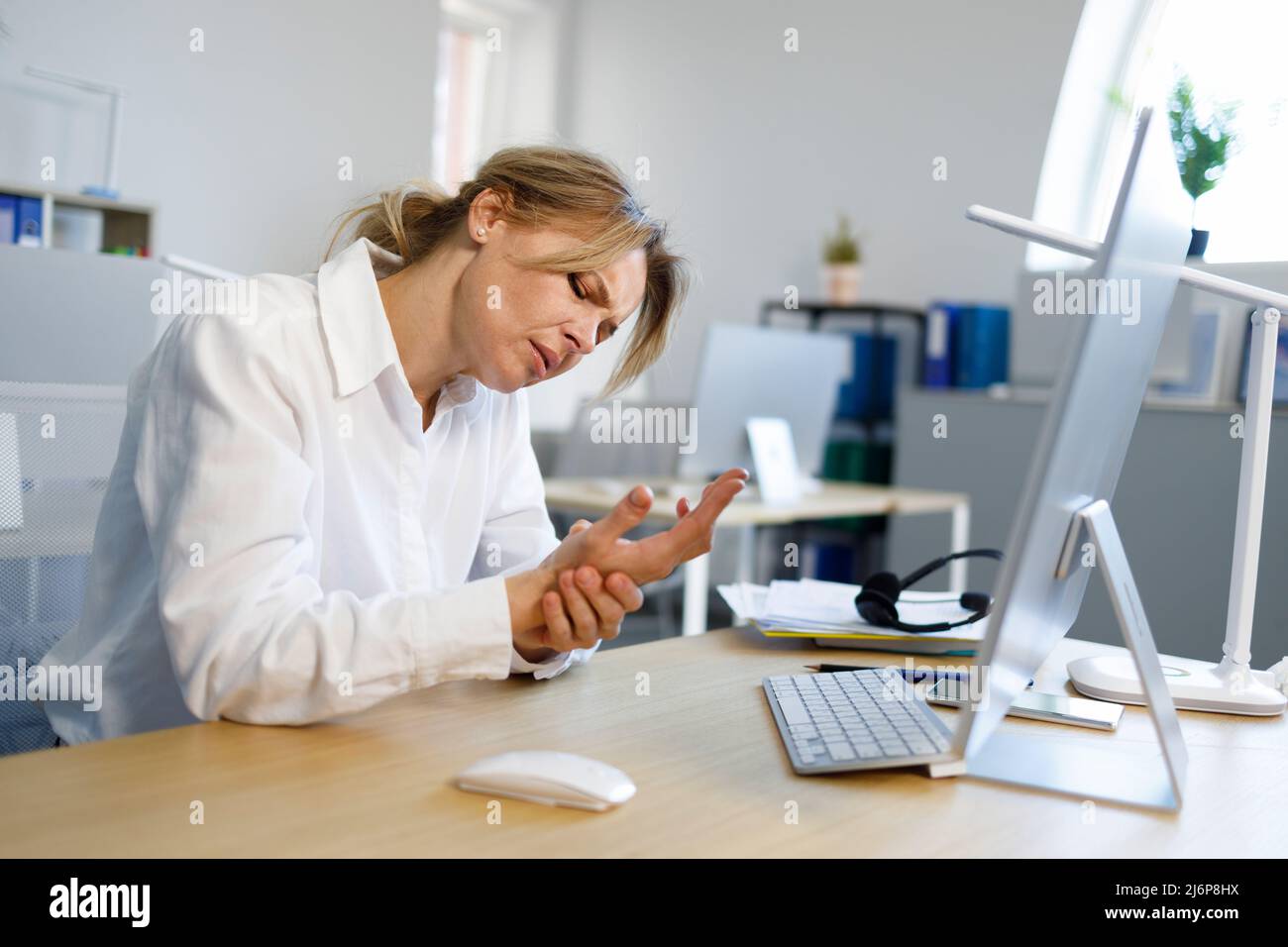 Business woman suffering carpal tunnel syndrome from intensely using mouse and typing on