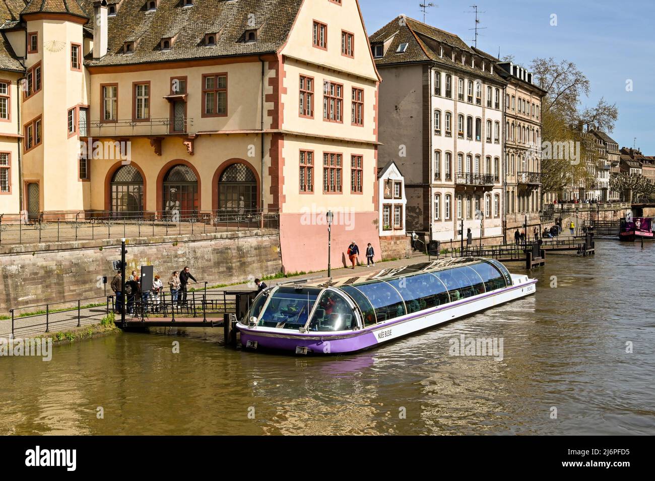 Strasbourg, France - April 2022: River cruise boat at a jetty picking up visitors for a trip on the River Ill which runs through the centre of the cit Stock Photo