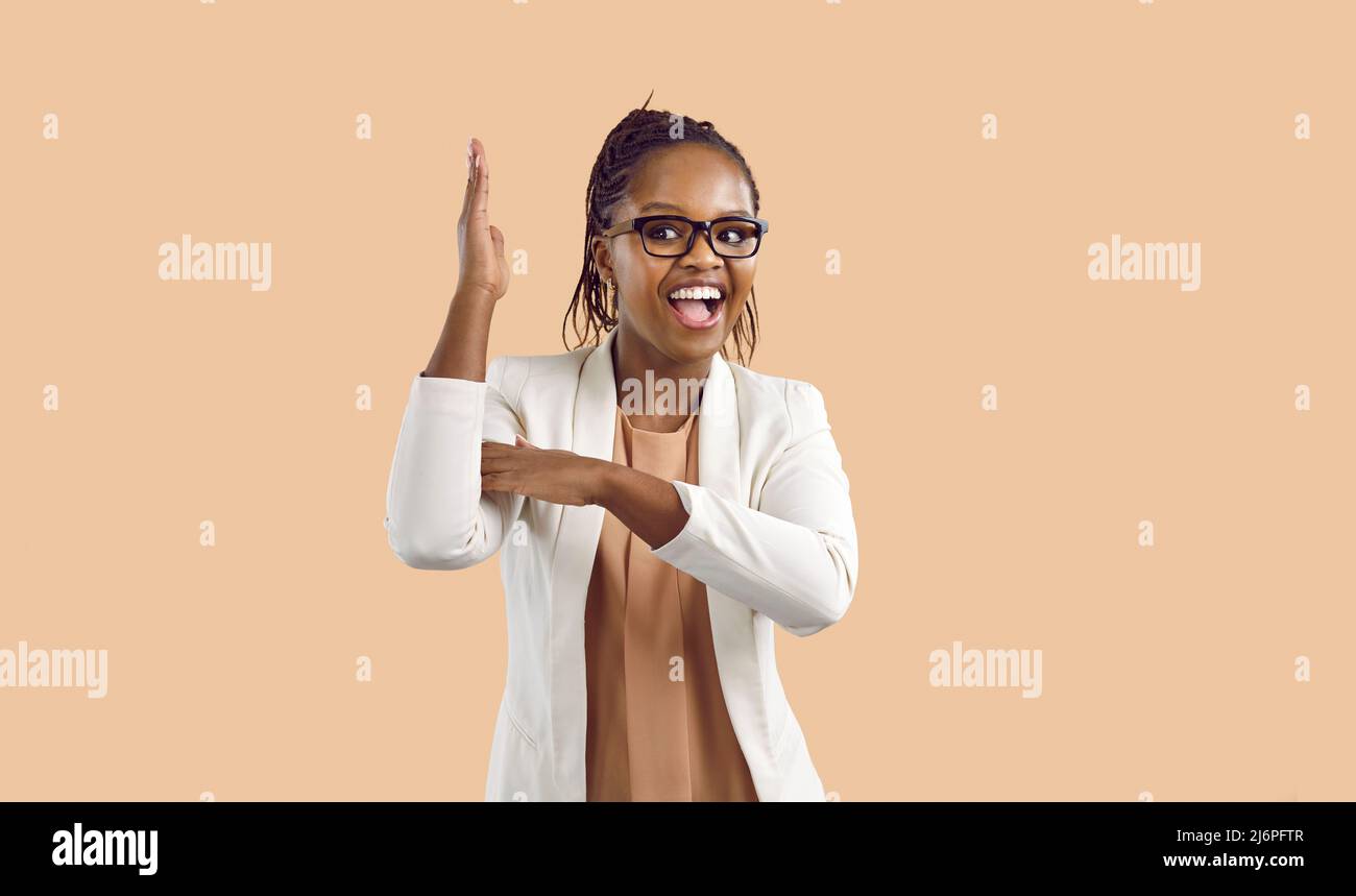 Woman raises her hand to attract attention and answer questions isolated on beige background. Stock Photo