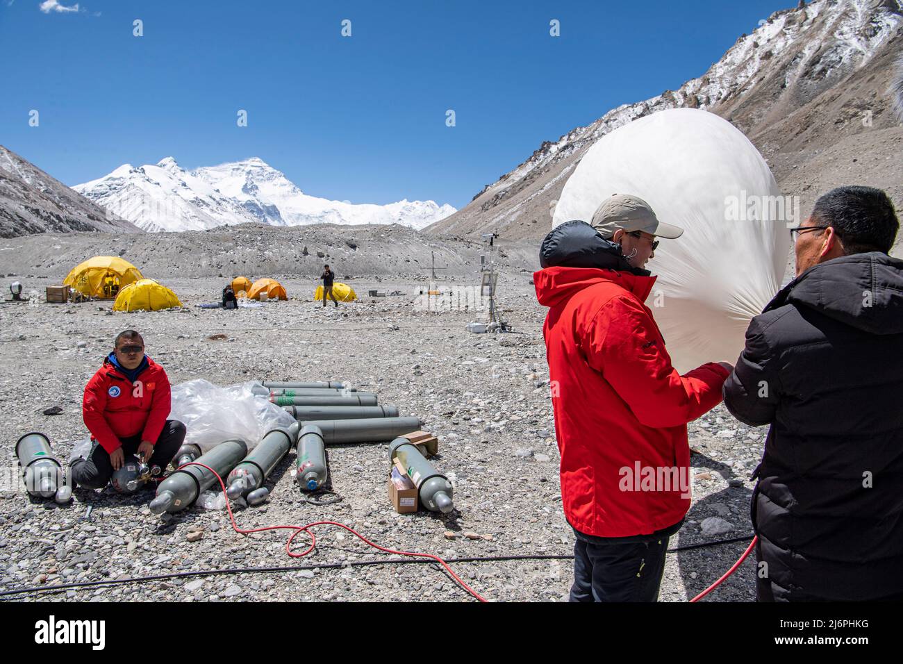 MOUNT QOMOLANGMA BASE CAMP, May 3, 2022 (Xinhua) -- Scientific research members inflate a weather balloon at the Mount Qomolangma base camp on May 3, 2022.  China has started a new comprehensive scientific expedition on Mount Qomolangma, the world's highest peak on the China-Nepal border.   Weather factors such as temperature, wind speed and humidity will directly affect the completion of scientific research tasks and the safety of research personnel at high altitude. Therefore, a meteorological support team has been launched in safeguards of the scientific expedition.   The team i Stock Photo