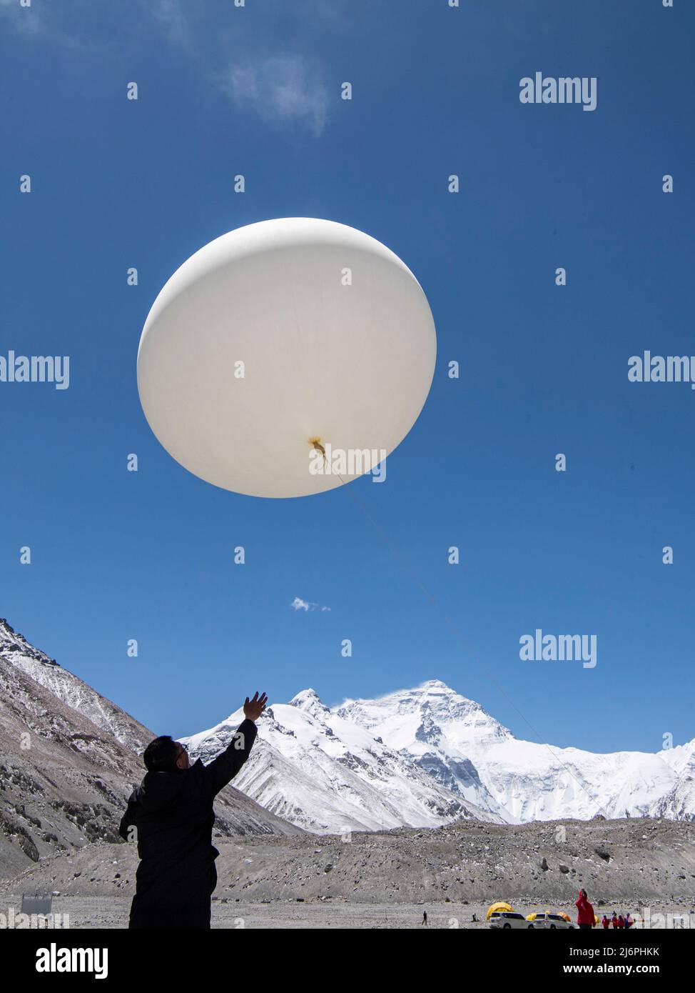 MOUNT QOMOLANGMA BASE CAMP, May 3, 2022 (Xinhua) -- A scientific research member launches a weather balloon at the Mount Qomolangma base camp on May 3, 2022.  China has started a new comprehensive scientific expedition on Mount Qomolangma, the world's highest peak on the China-Nepal border.   Weather factors such as temperature, wind speed and humidity will directly affect the completion of scientific research tasks and the safety of research personnel at high altitude. Therefore, a meteorological support team has been launched in safeguards of the scientific expedition.   The team Stock Photo