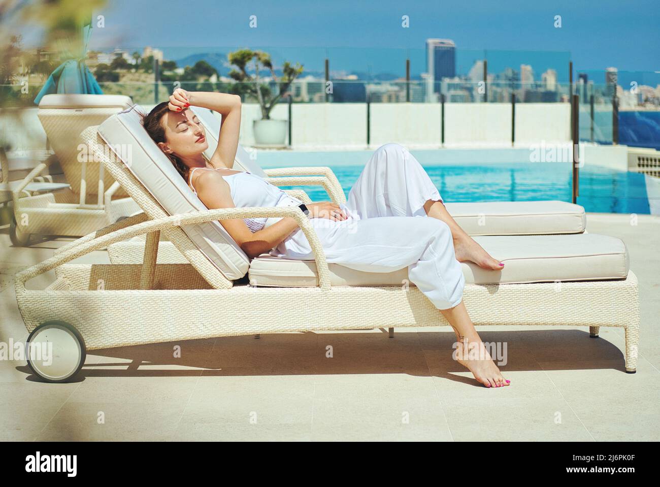 Young slim woman wear white summer suit relaxing alone lay on sunbed ...