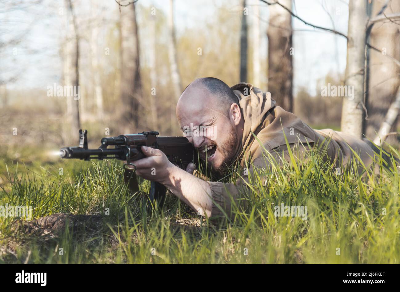 warrior shoots from a machine gun lying on the ground Stock Photo