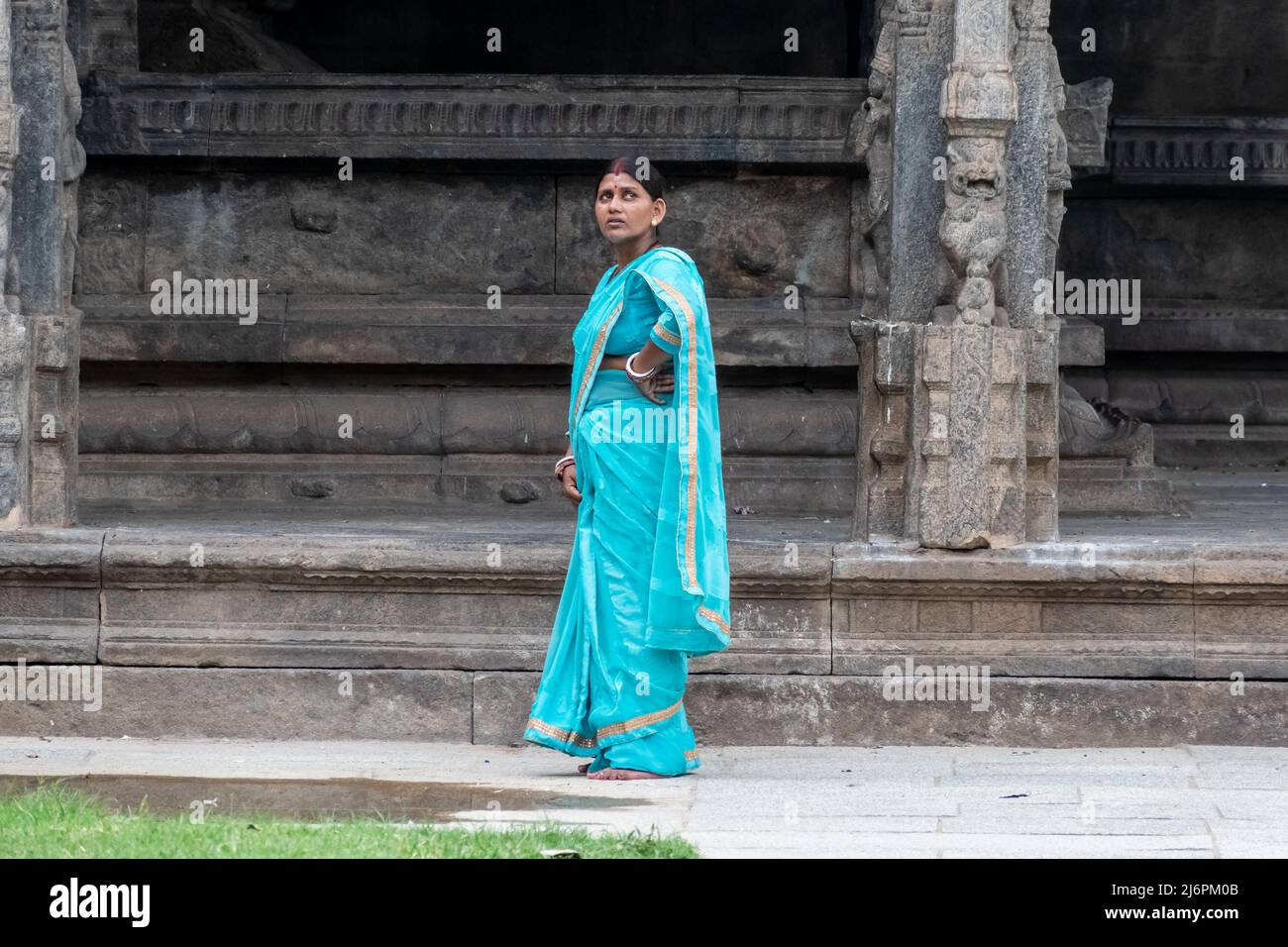 Vellore, Tamil Nadu, India - Septermber 2018: An Indian woman wearing a bright blue sari standing outside and staring at the walls of a temple in the Stock Photo