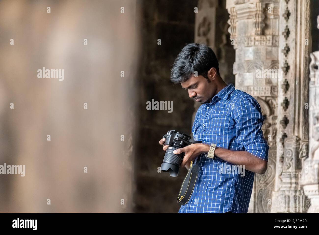 Vellore, Tamil Nadu, India - September 2018: An Indian male tourist photographer checking images on his camera at the ancient Vellore fort temple. Stock Photo